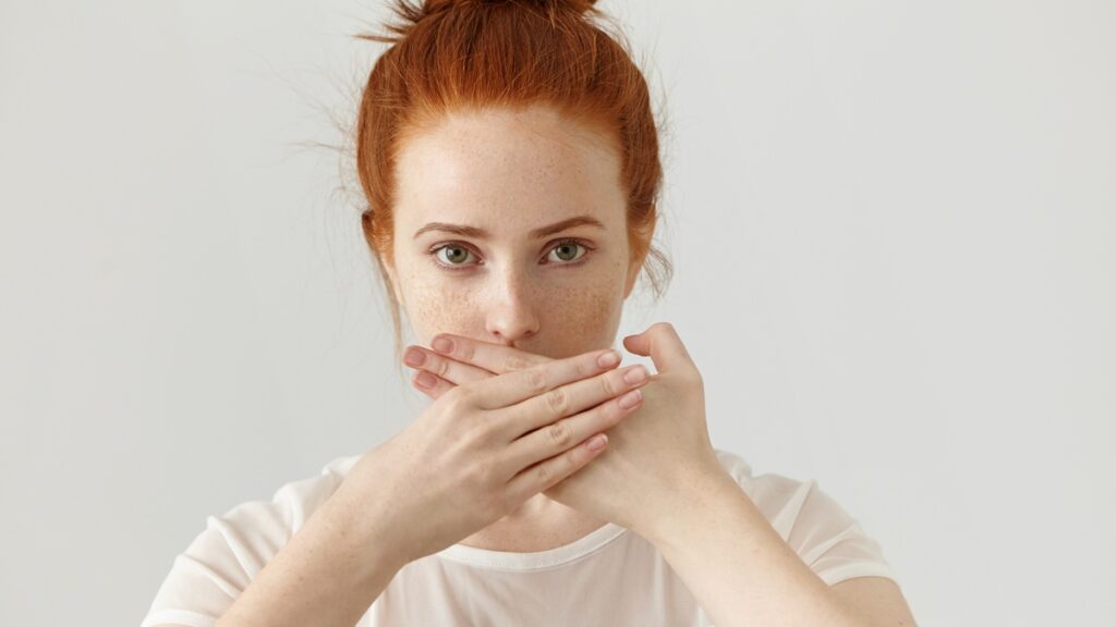 nő szájra tett kézzel